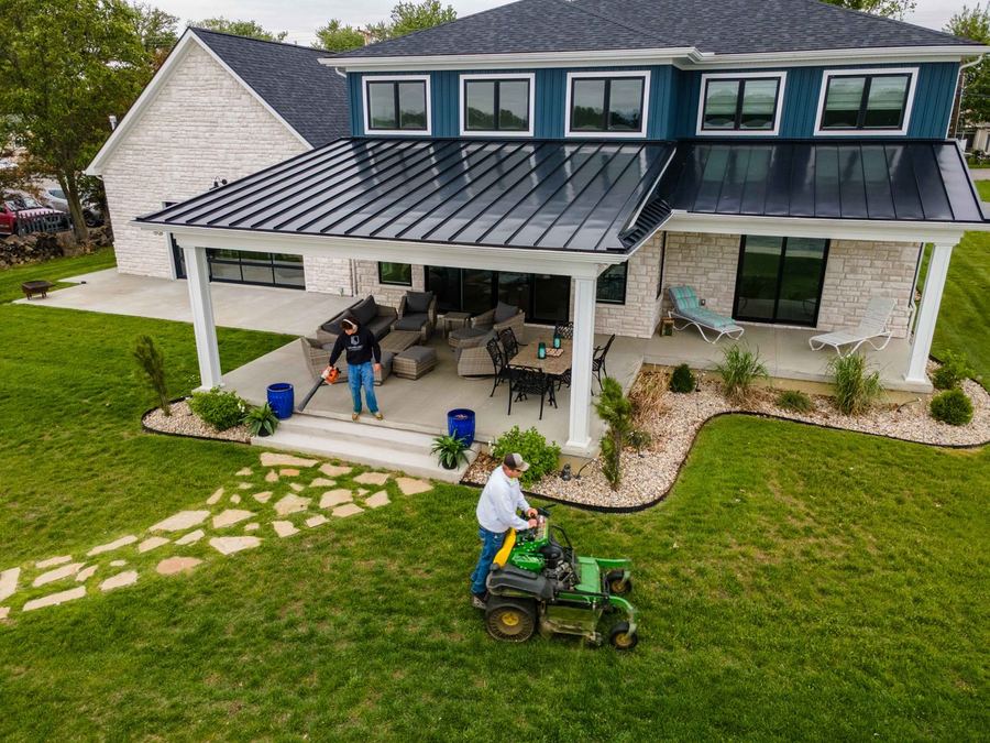 Aerial view of a Logan Lawn & Landscaping crew mowing a lakefront property