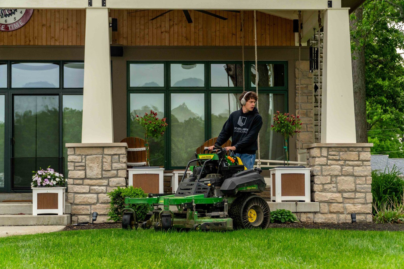 Logan Lawn & Landscaping crew member on a John Deere stand-on mower