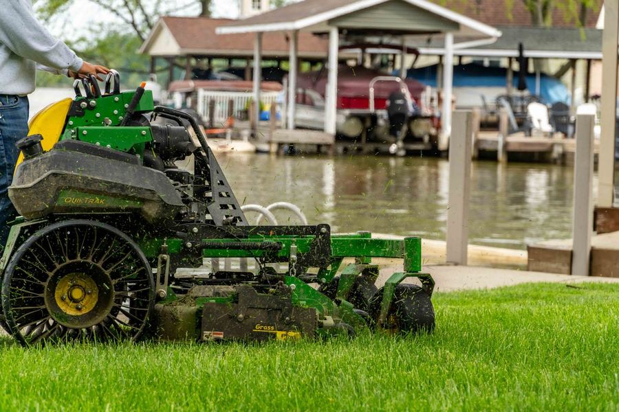 John Deere QuikTrak stand-on mower along a lakeside dock
