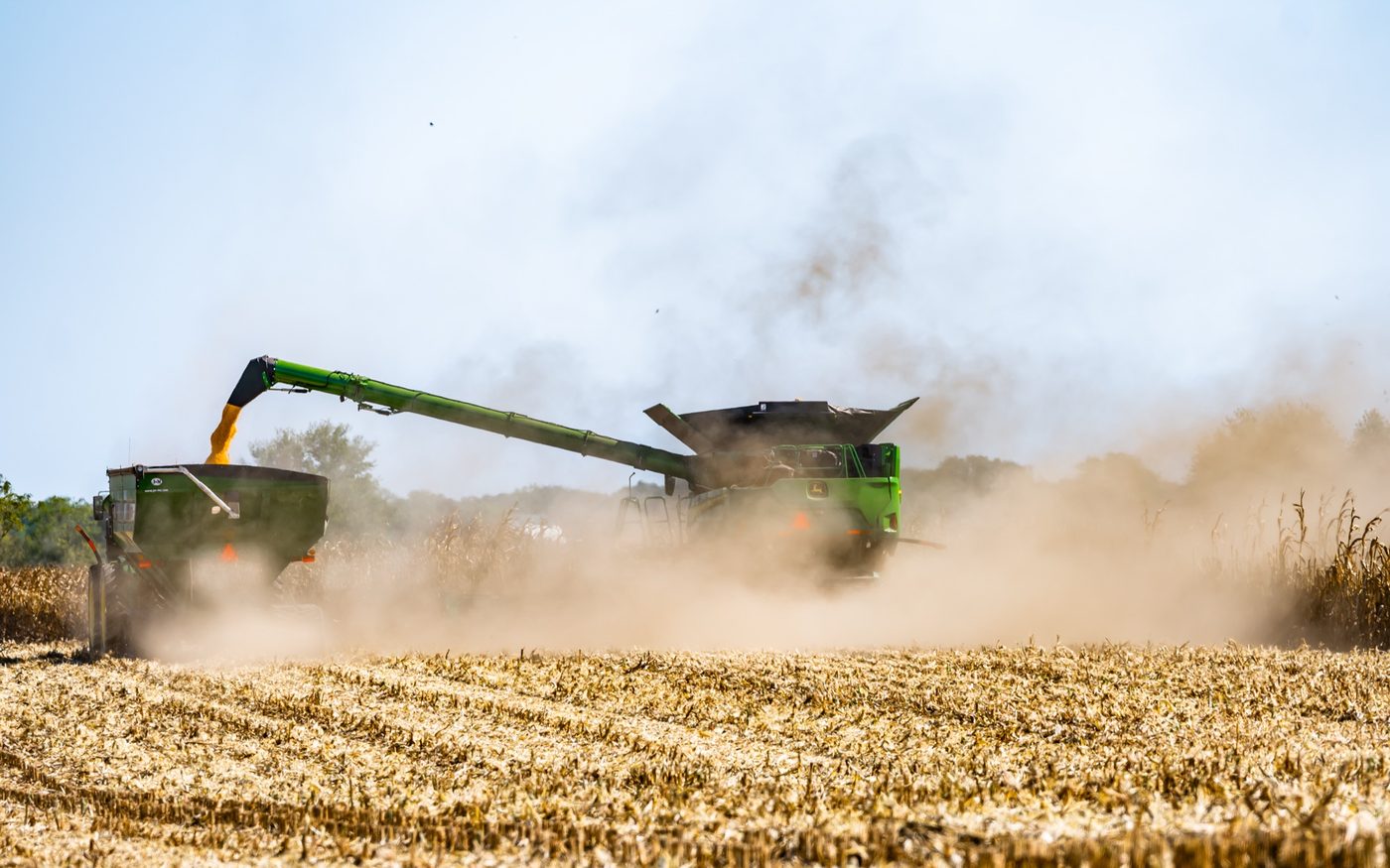 A John Deere combine unloading into a grain cart on the go during harvest