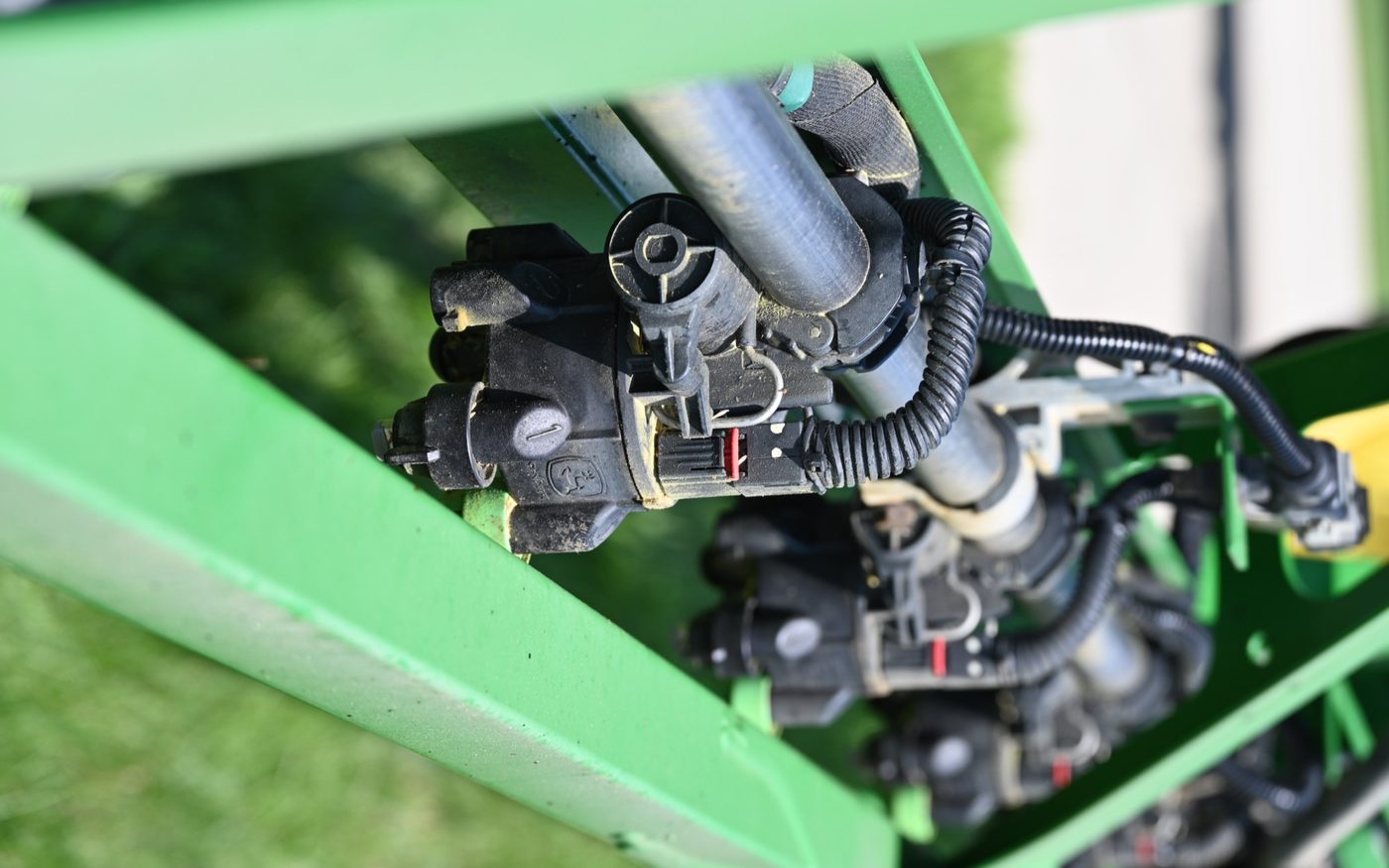 Close-up of the nozzles and plumbing on a Miers Farm Corp John Deere sprayer boom