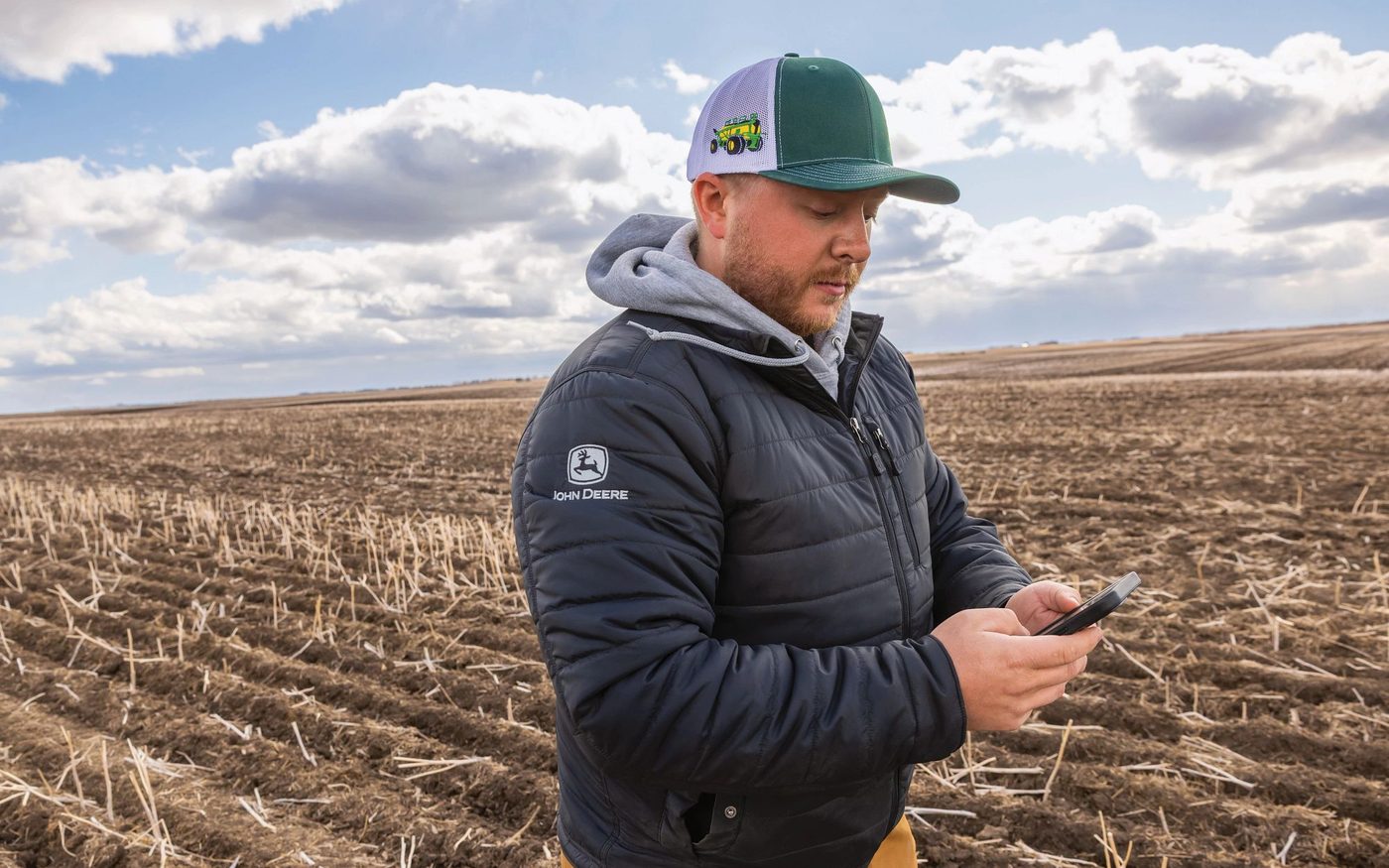 A farmer checking field information on his smartphone in a harvested field