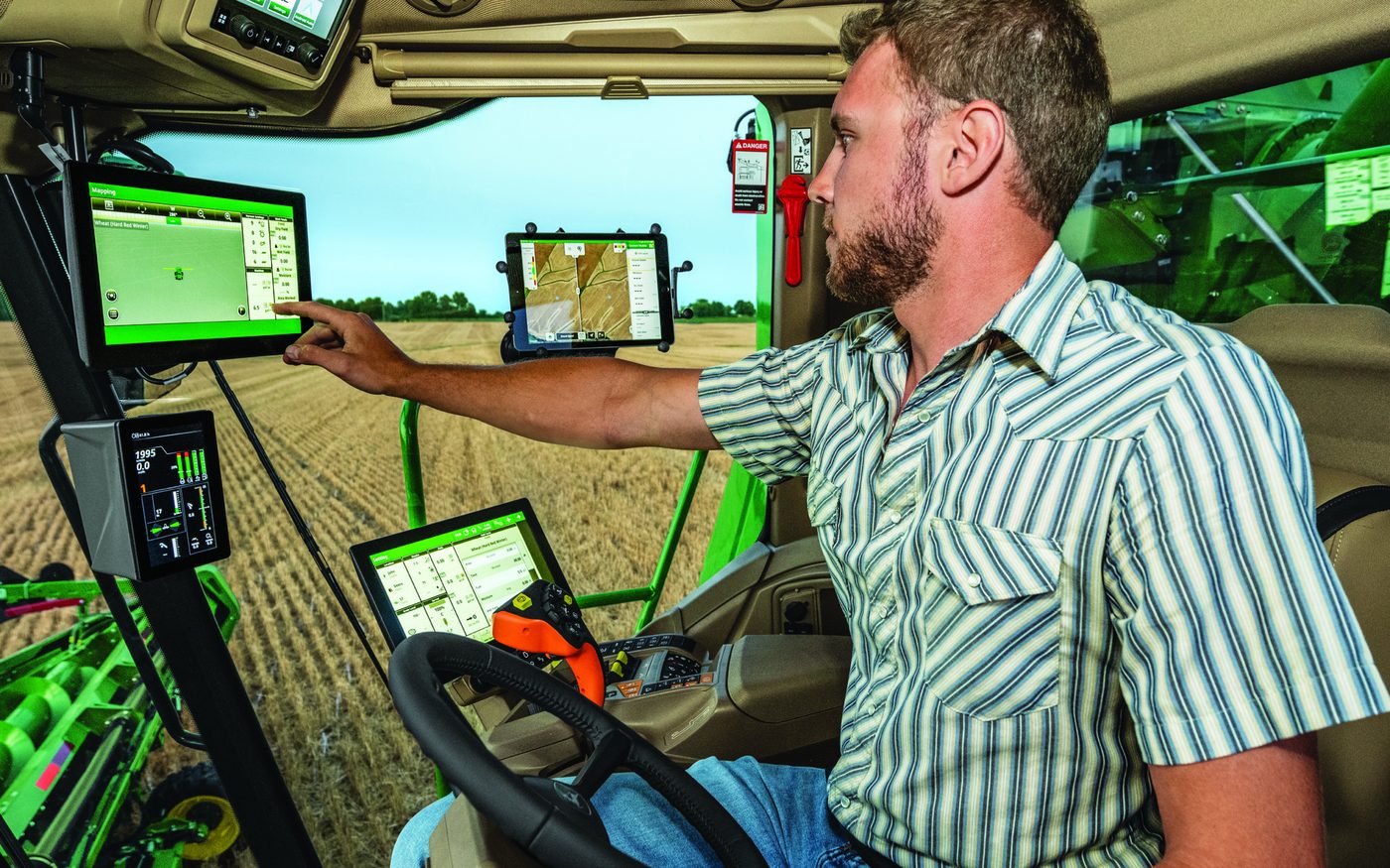 An operator using John Deere in-cab displays with guidance running