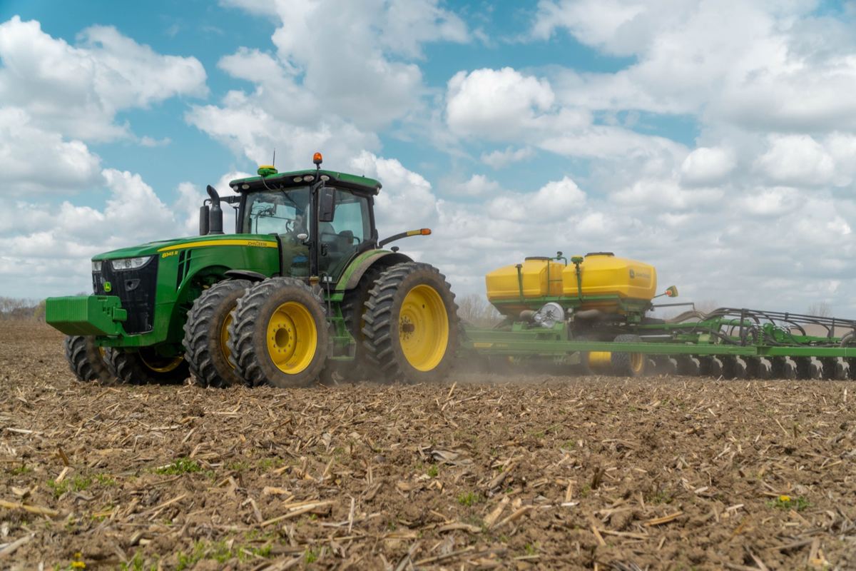 John Deere 8R 410 tractor pulling a planter in a field under a cloudy sky