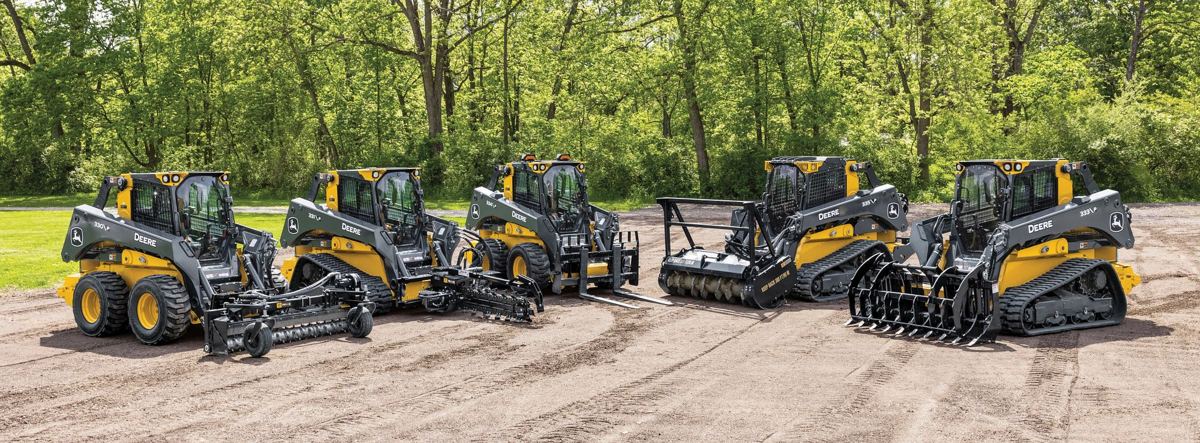 Five John Deere G-Series compact construction machines with various attachments on dirt