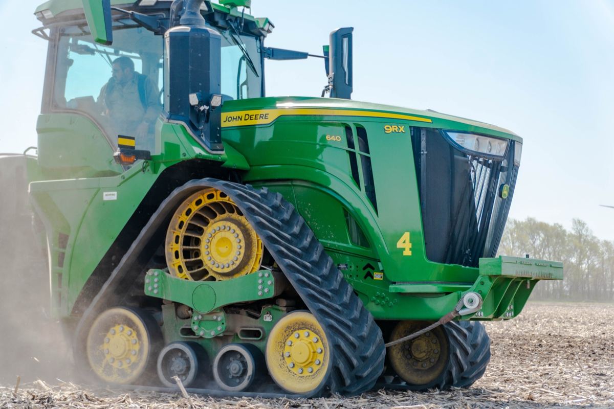 Green John Deere 9RX 640 track tractor with a man in the cab working in a field