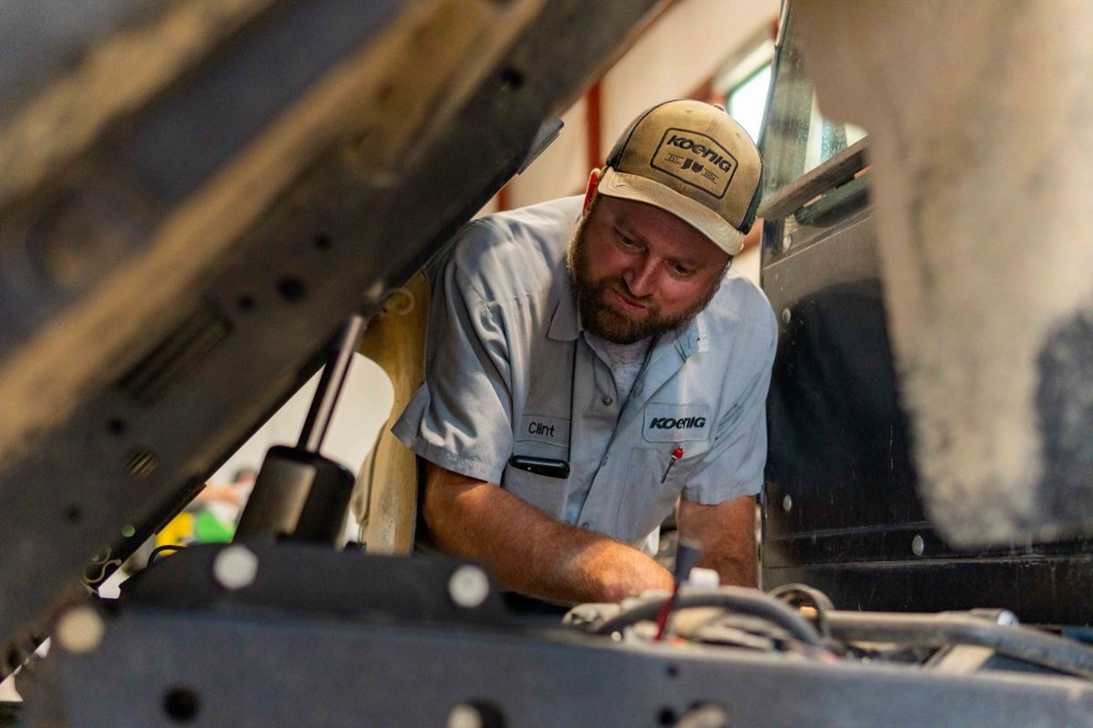 A Koenig Equipment mechanic is repairing the engine of heavy equipment in a service shop