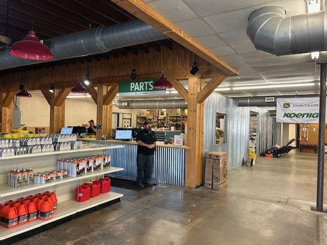 Interior view of a Koenig Equipment John Deere parts department with a counter, shelves, and a banner