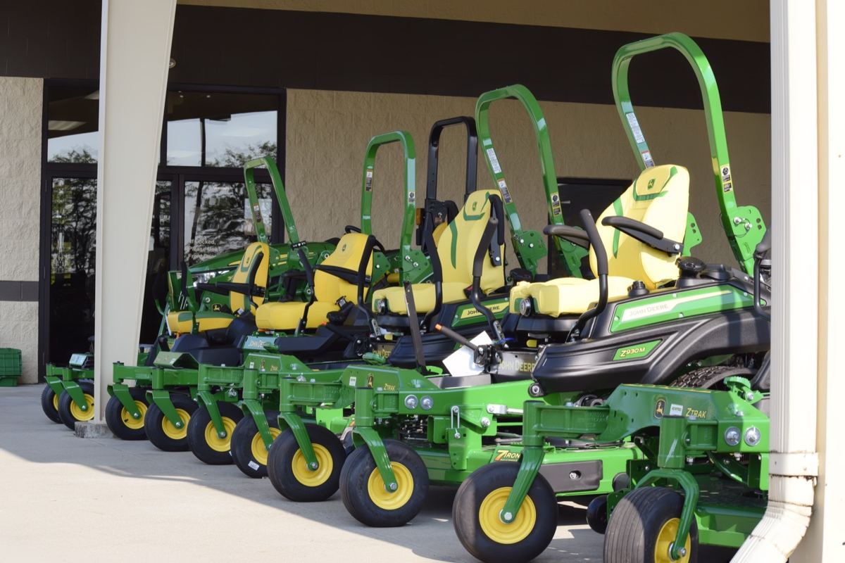 A row of John Deere ZTrak zero-turn mowers on display outside a Koenig Equipment store