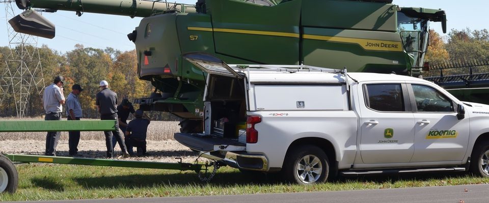 Koenig Equipment service truck and technicians with a John Deere combine at a customer site