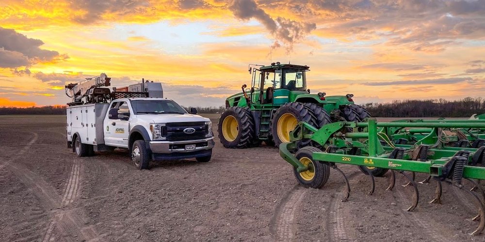 Koenig Equipment service truck out in the field beside a John Deere tractor and tillage tool