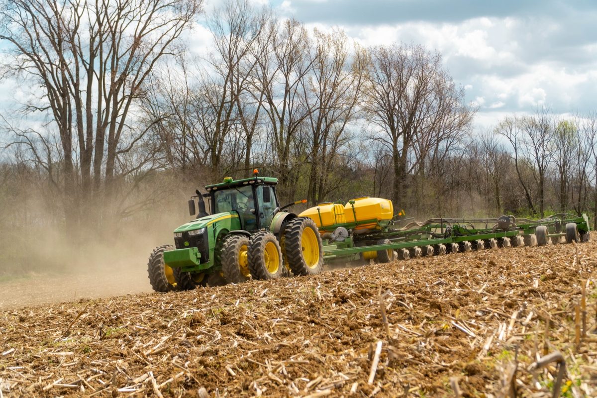 John Deere 8R tractor pulling a planter across a field during spring planting at a Koenig Customer farm