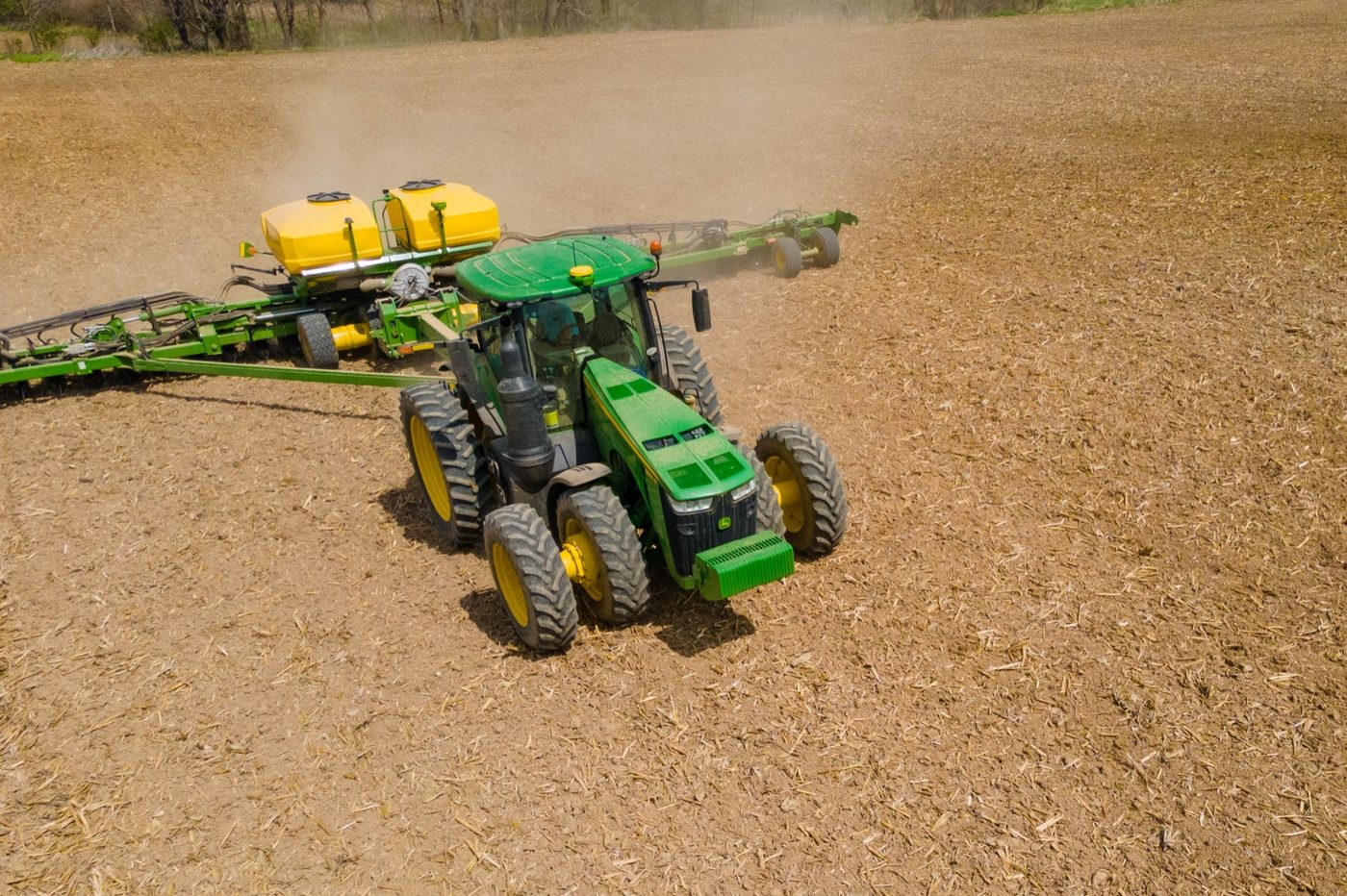 Aerial view of a John Deere tractor and planter turning at the end of a field during spring planting