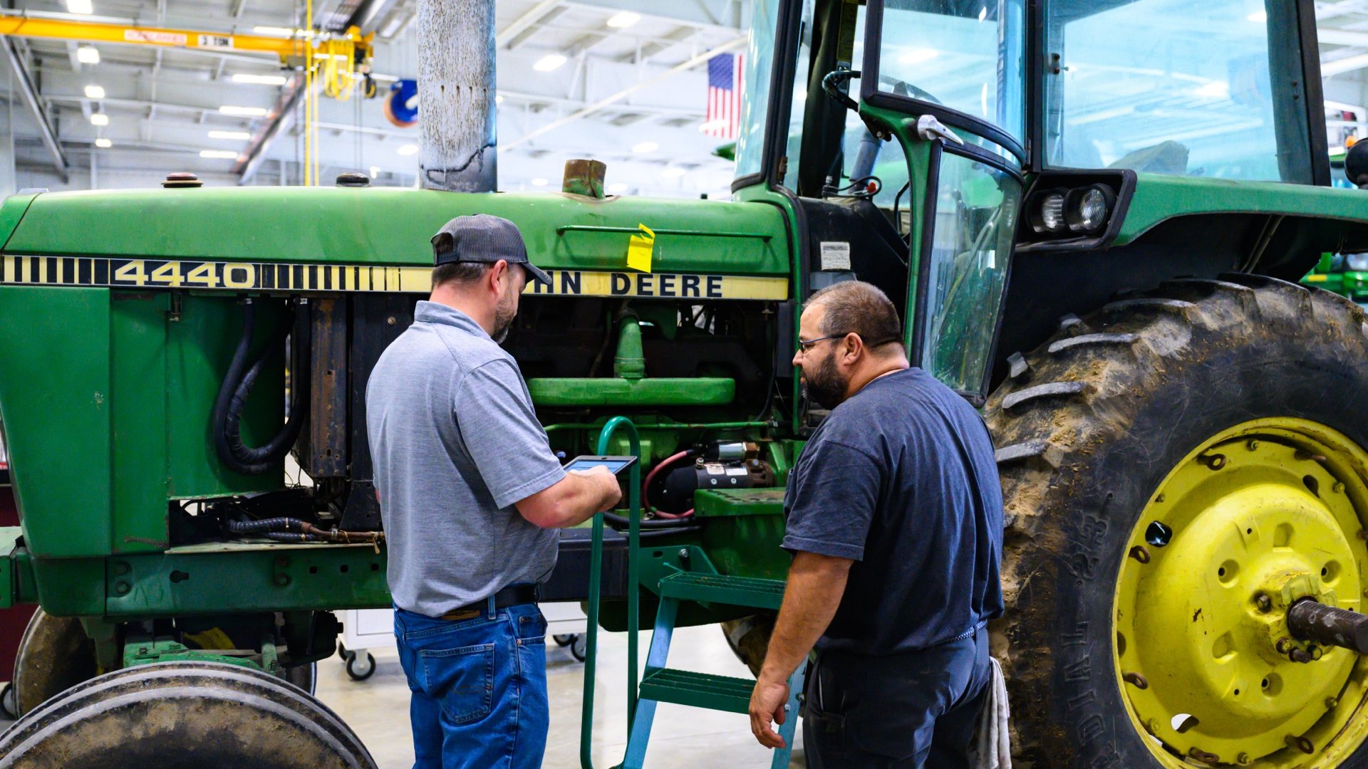 Koenig technician inspecting a John Deere tractor with a tablet