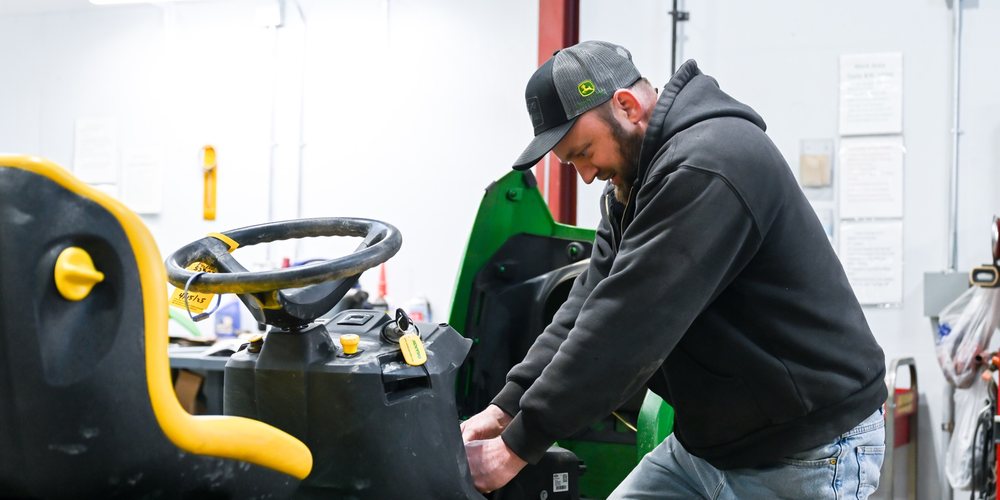 Koenig technician inspecting a John Deere riding mower