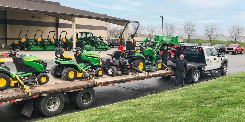 Koenig truck and trailer loaded with John Deere mowers and a compact tractor for delivery