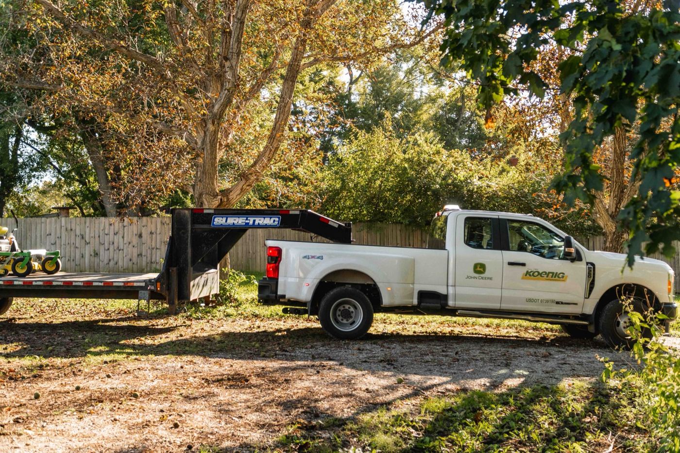 A Koenig Equipment truck and trailer pulling onto a Customer's rural property