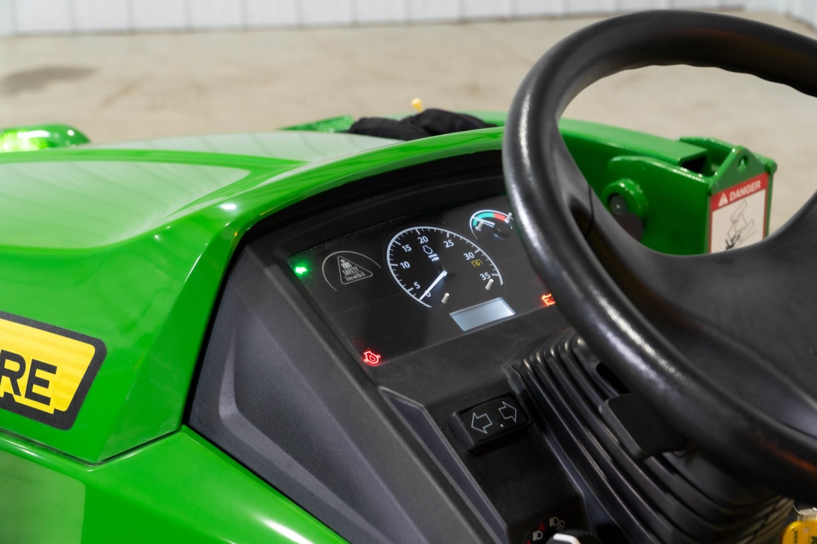 Close-up of the John Deere 1025R tractor's dashboard, steering wheel, and control levers