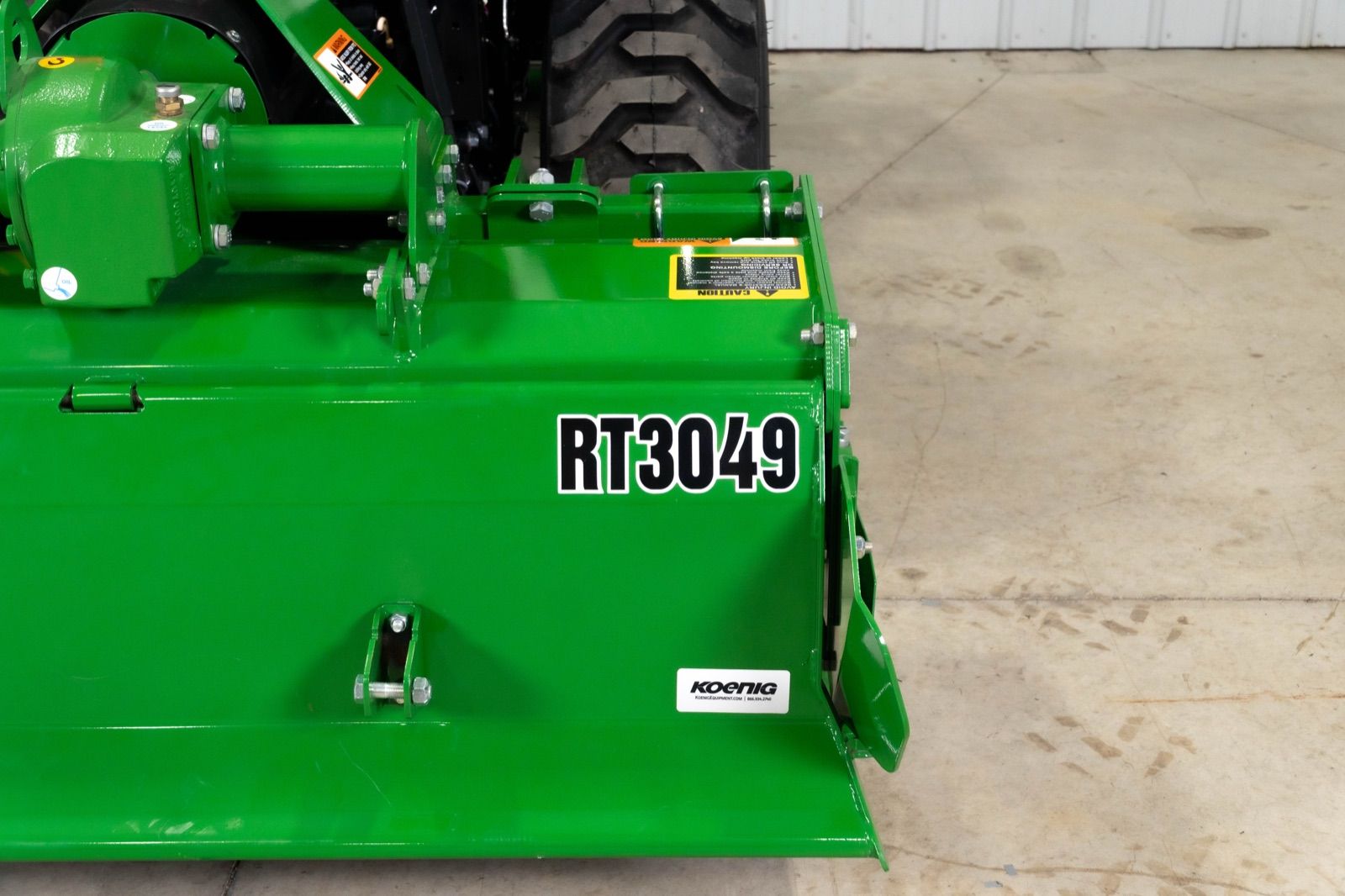 Close-up view of the green RT3049 rotary tiller attached to the rear of the tractor