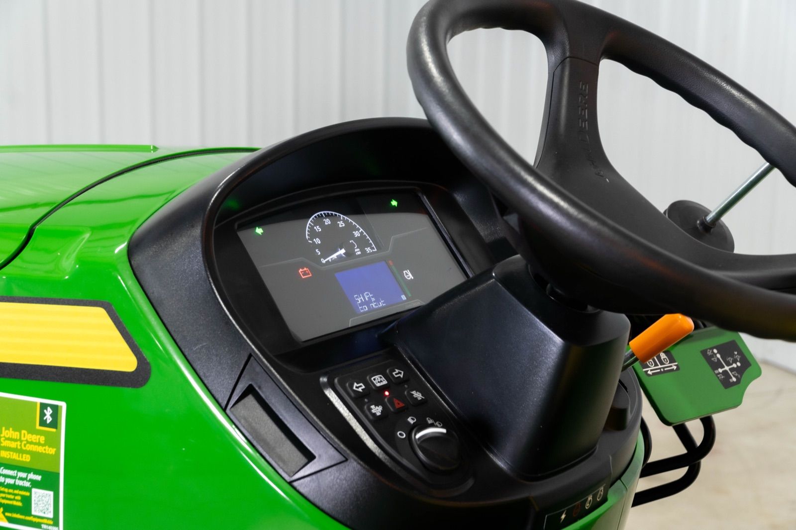Close-up of the John Deere 3032E dashboard, steering wheel, and control panel