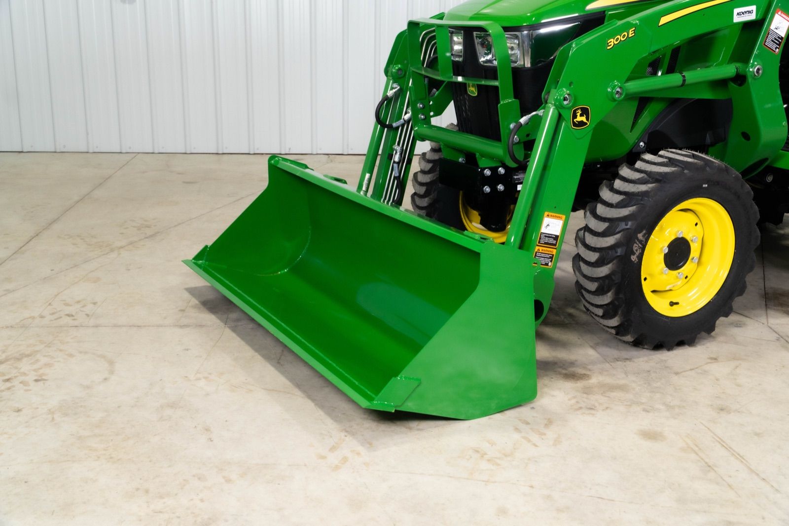 Close-up of the green 300E loader with a wide bucket attachment