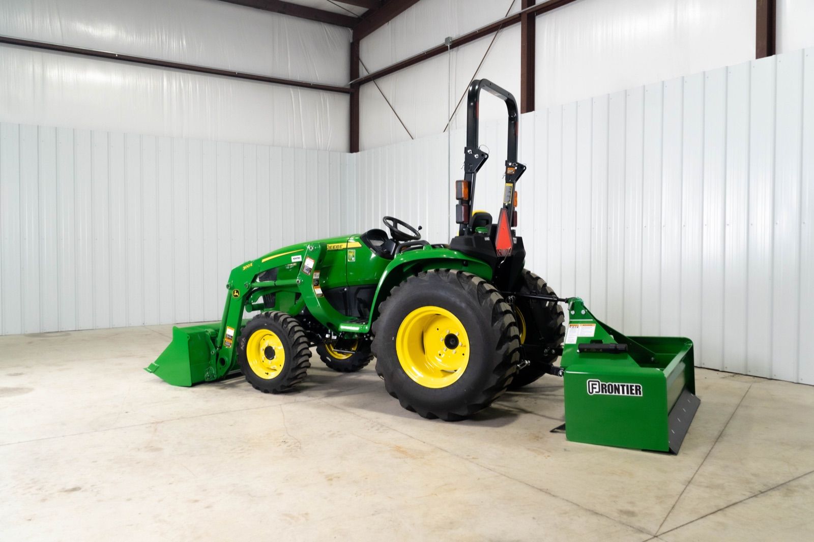 Rear three-quarter view of John Deere 3032E tractor with 300E loader and box blade