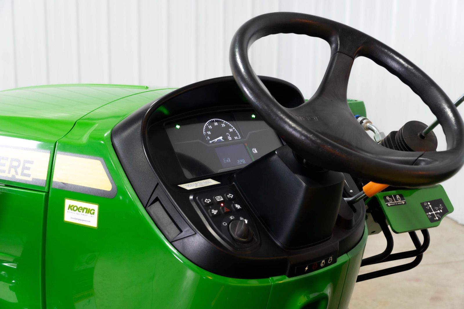 Interior view of the John Deere 3038E tractor showing the black steering wheel and dashboard controls