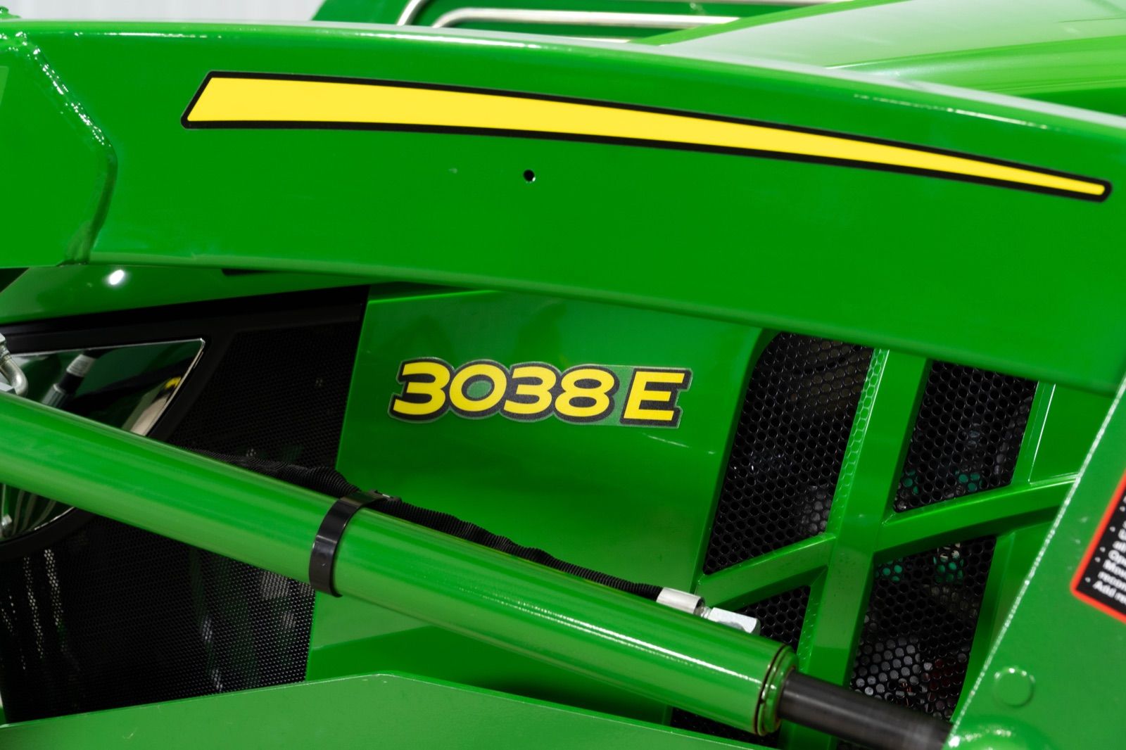 Close-up of the 3038E model number decal on the green hood of the John Deere 3038E tractor