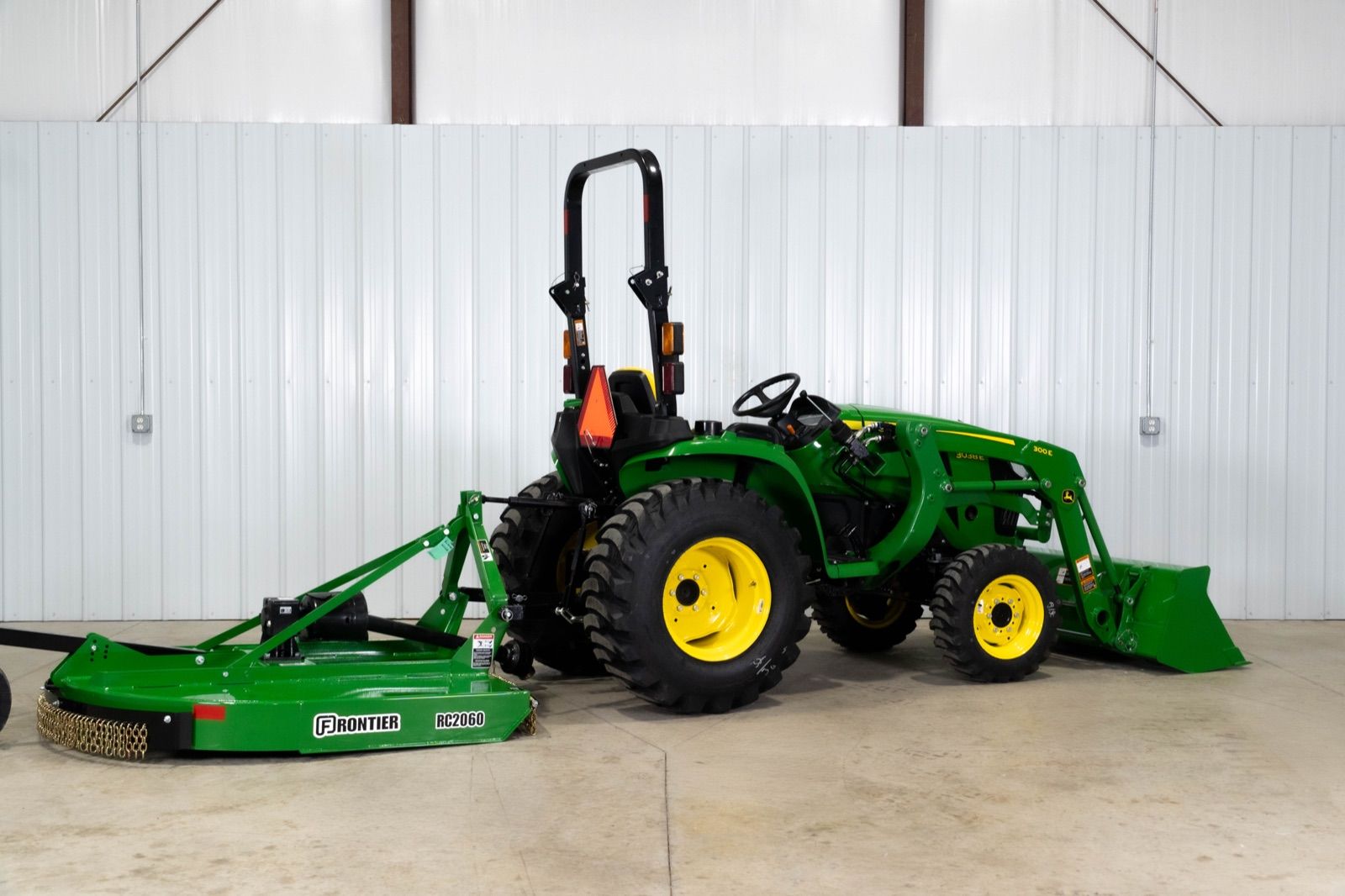Three-quarter rear view of the John Deere 3038E tractor with 300E loader and RC2060 rotary cutter