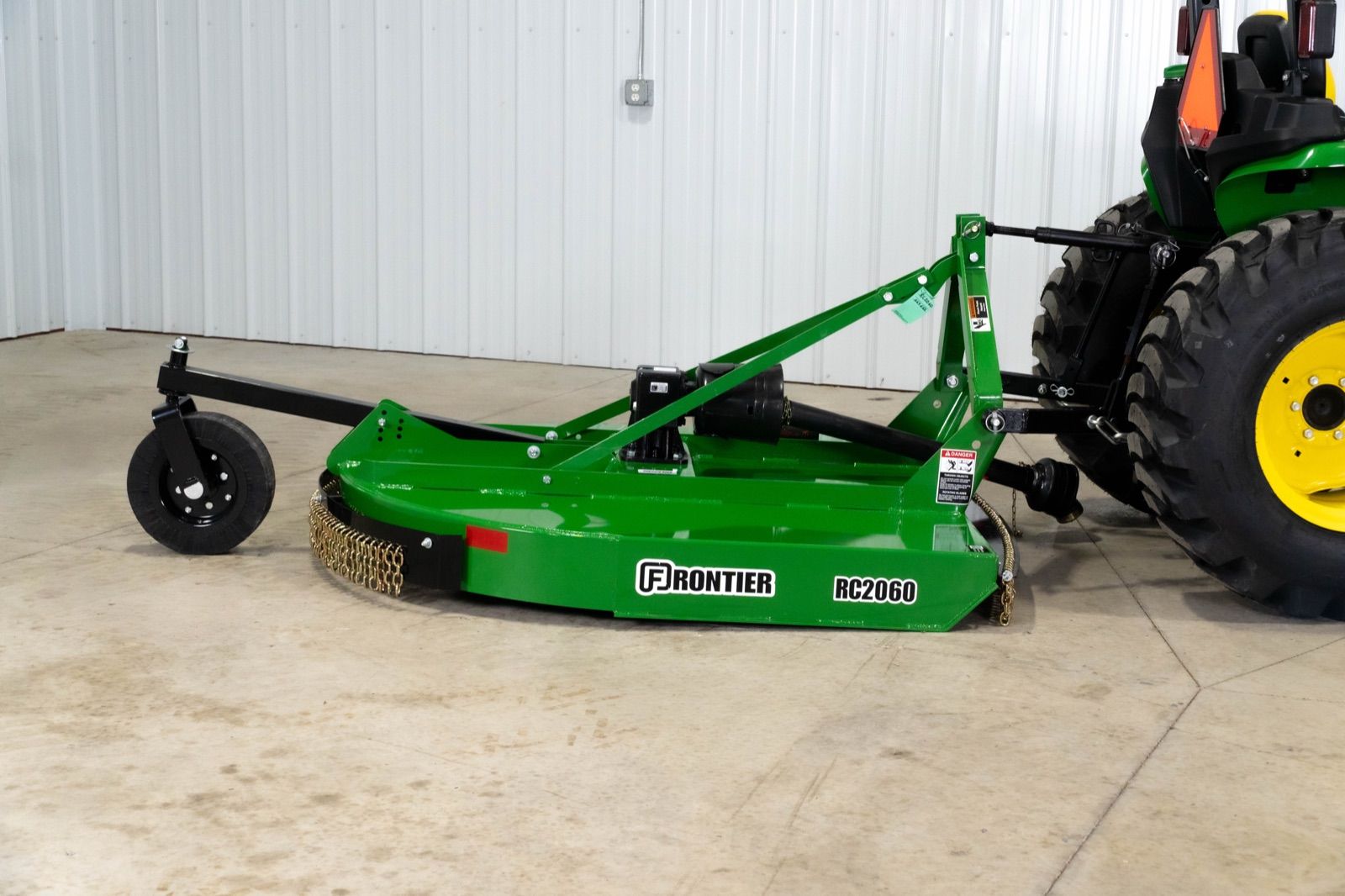 Rear close-up of the green Frontier RC2060 rotary cutter attached to the John Deere 3038E tractor