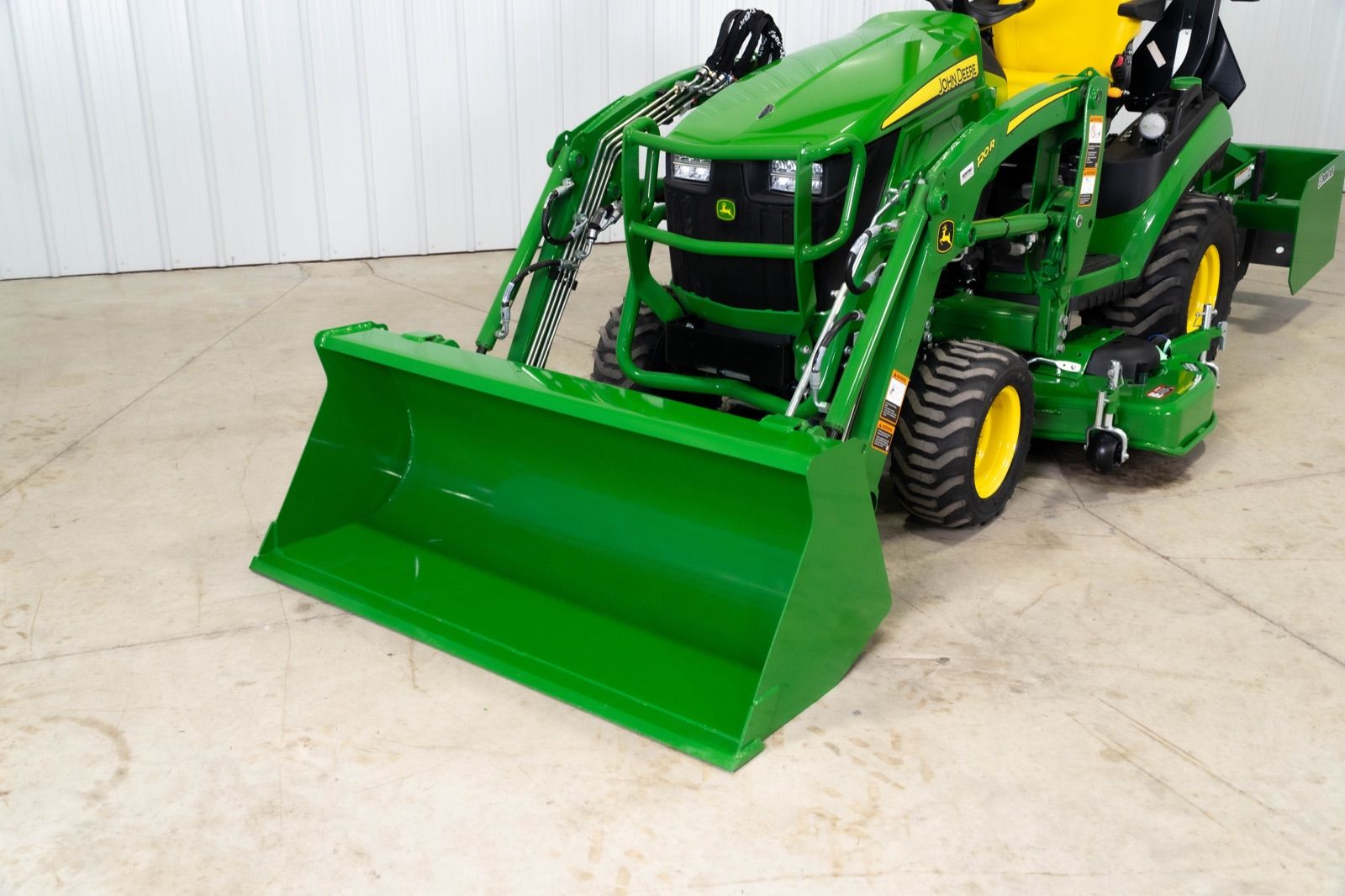 Close-up of the 120R loader and bucket on the John Deere 1025R tractor from the front left
