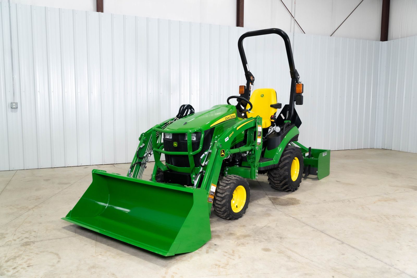 John Deere 1025R Warrior package, front view with the 120R loader bucket lowered