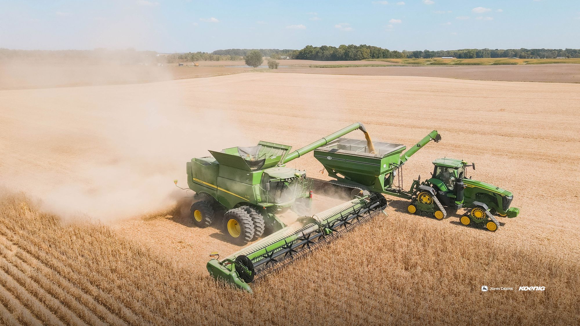 John Deere S7 combine unloading soybeans into a grain cart during harvest, October 2026 Koenig Equipment wallpaper